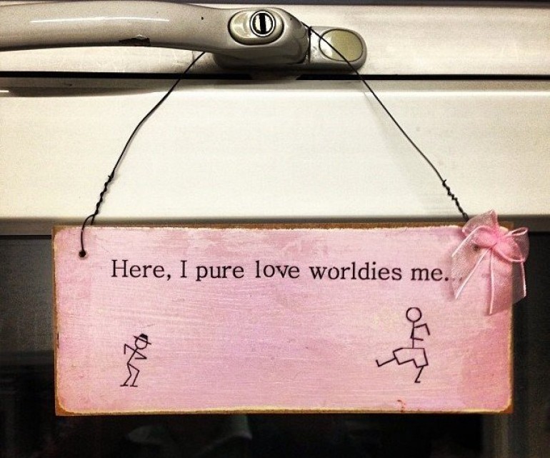 A handmade pink sign reading, 'Here, I pure love worldies me...'